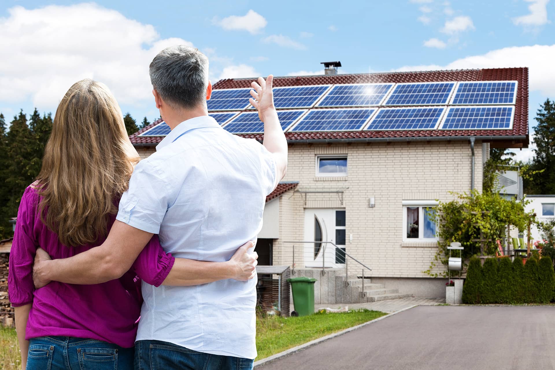 Happy couple with solar panels on their roof